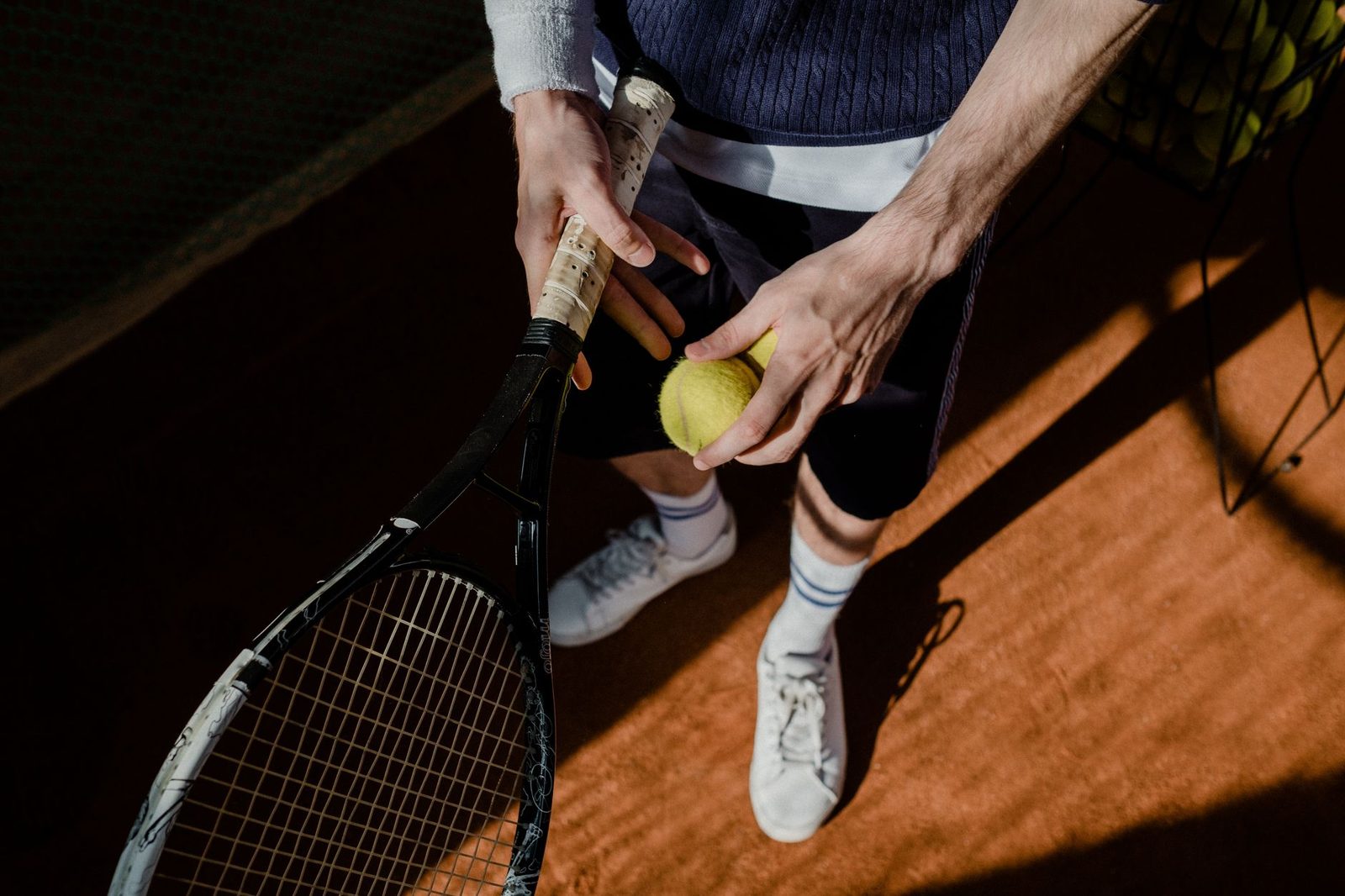 Player holding the racquet and ball on a clay court while preparing to serve