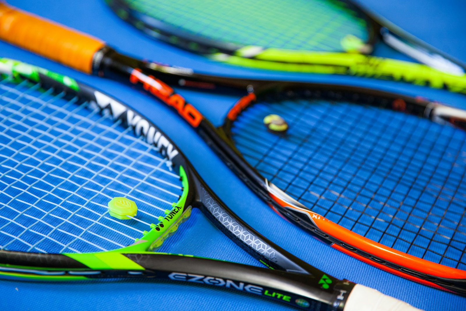 A green and black tennis racquet showing grip and strings