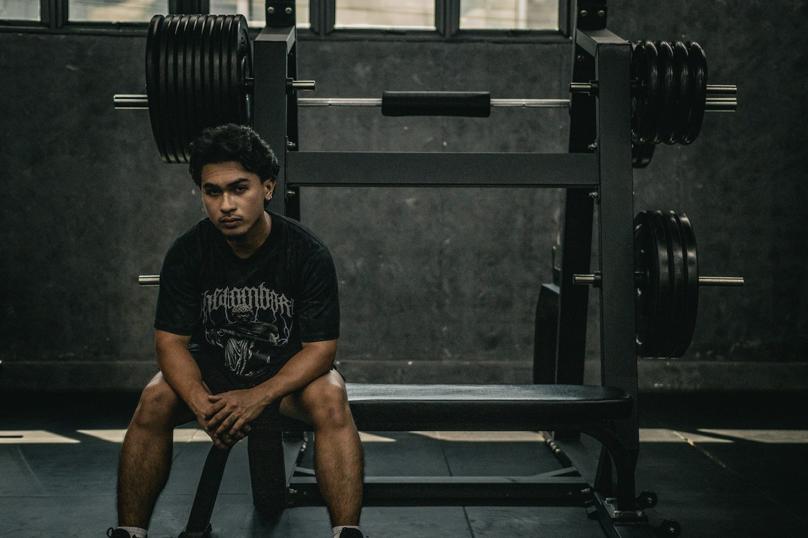 A man sitting on a bench in a gym, resting