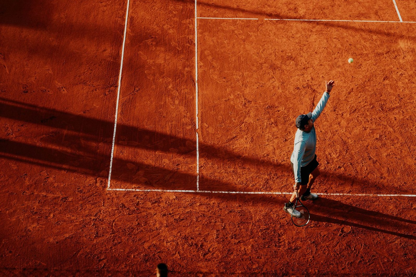 Overhead view of a player serving on a clay court