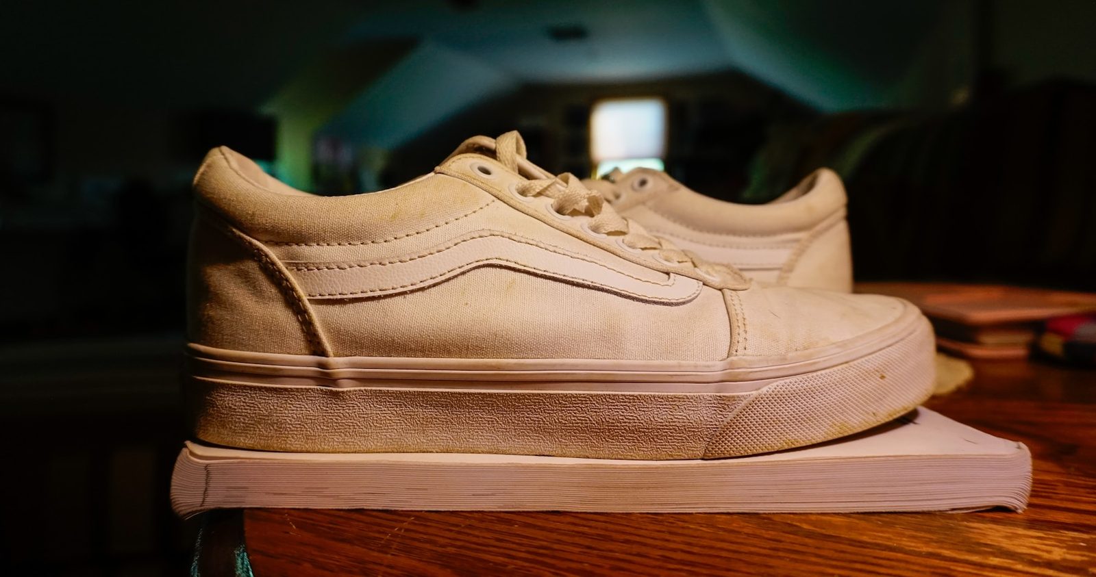 A white canvas shoe resting on a wooden table