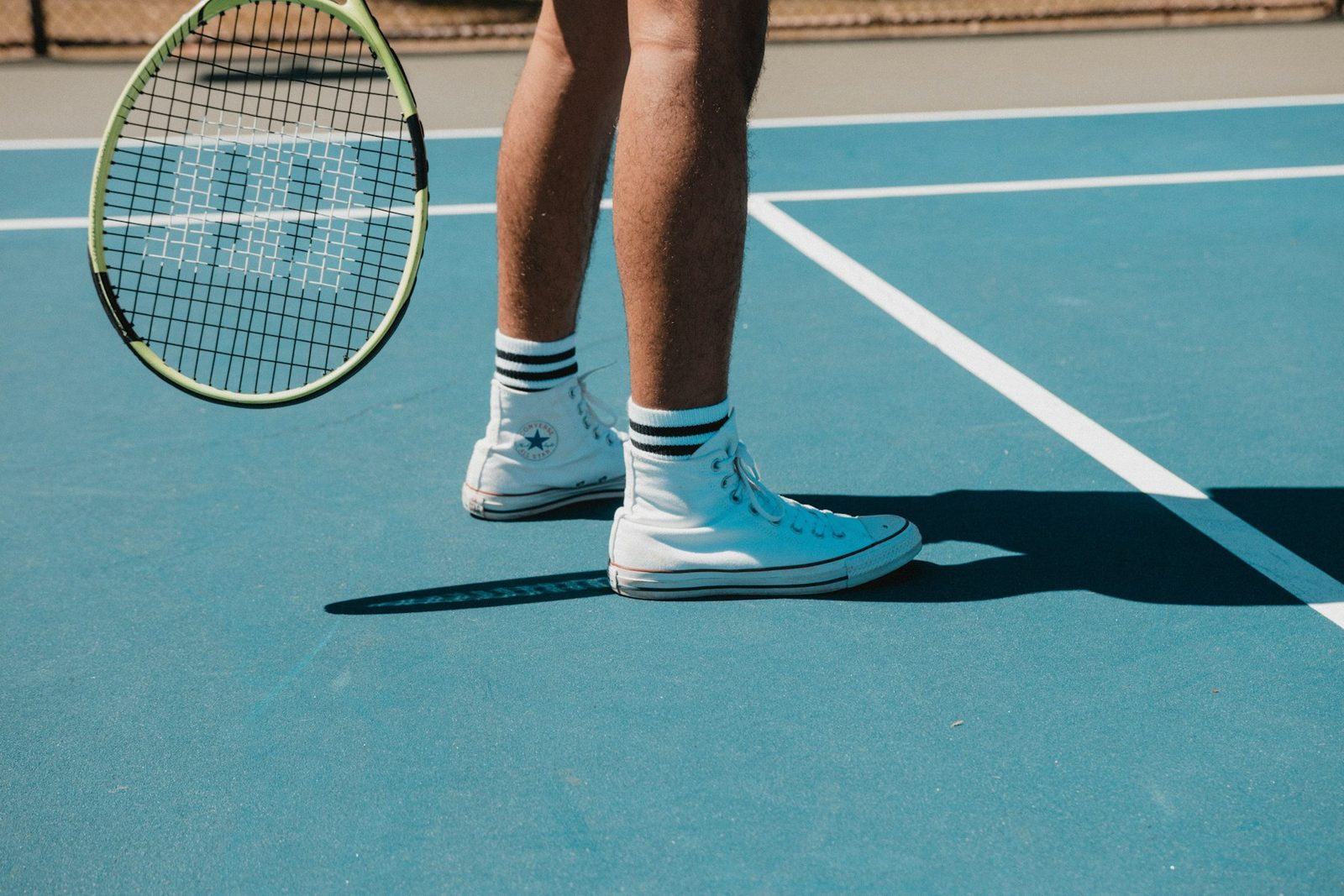 A person in white trainers standing on a tennis court