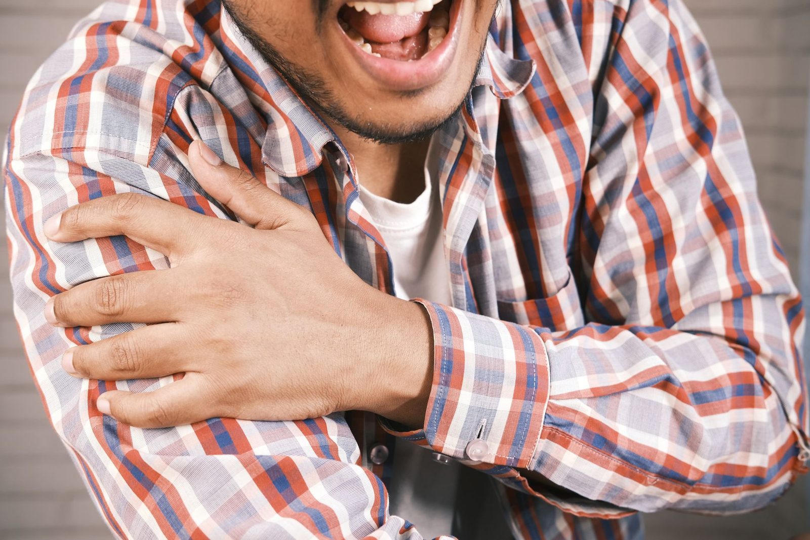 Close view of a man grasping his arm with shoulder pain
