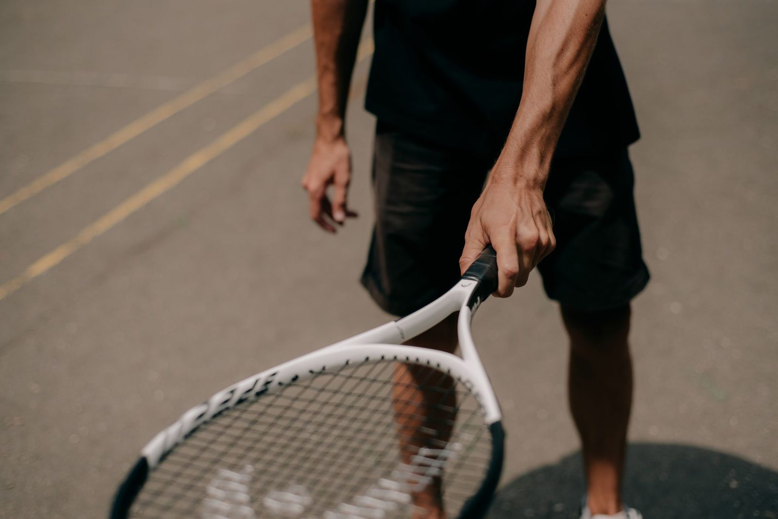 Close view of a player holding a tennis racquet on an outdoor court