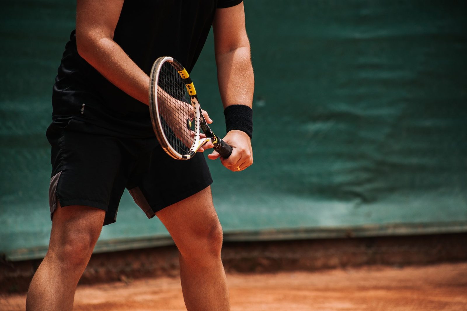 Close view of a tennis player holding the racquet, ready to serve on an outdoor clay court