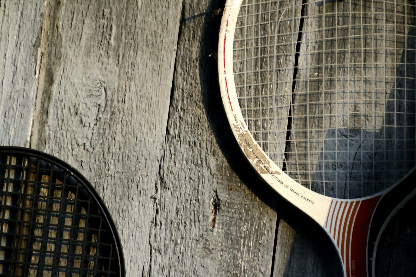 Two vintage tennis racquets leaning against a wooden wall