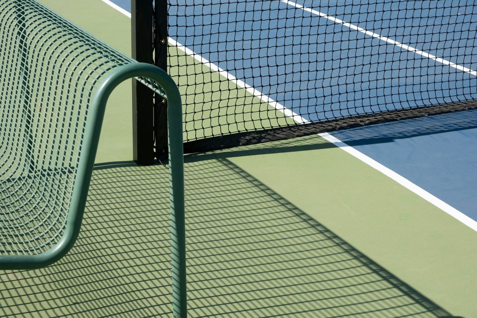 A green and white tennis court seen from the side