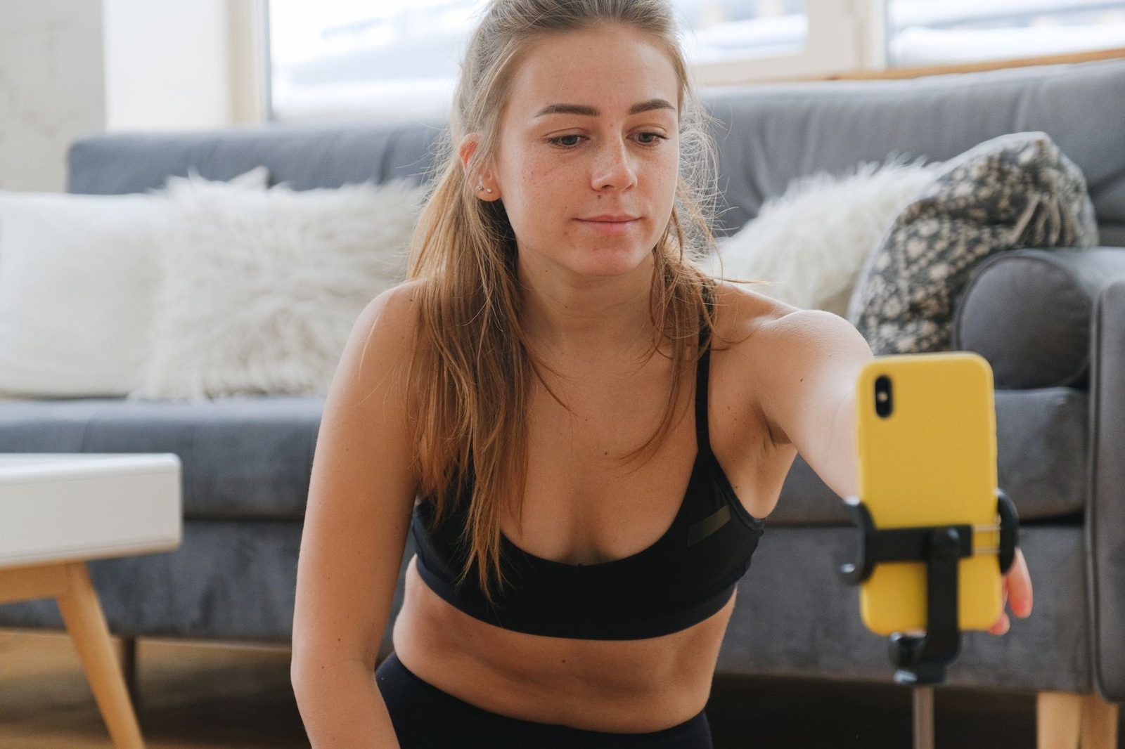 A young woman recording video on a smartphone mounted on a tripod