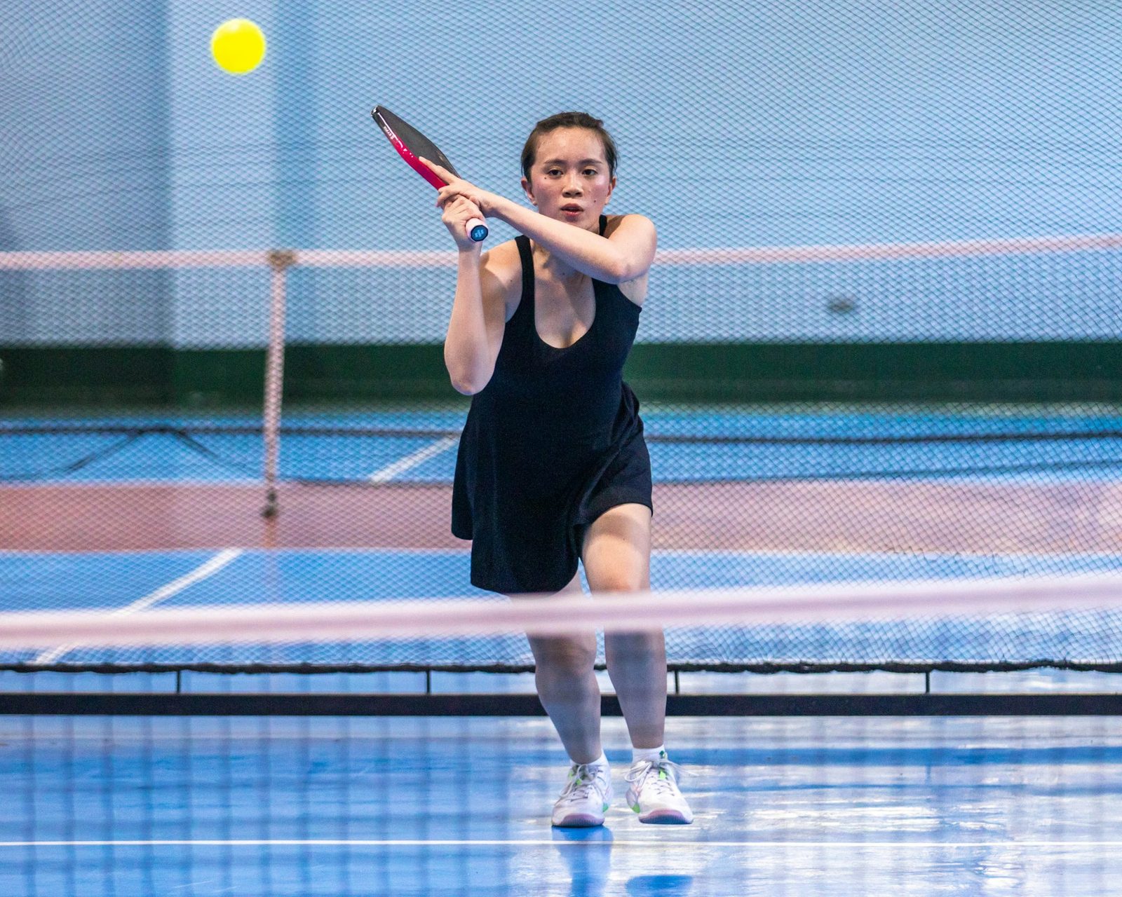 Player moving forward to take the ball early during an indoor net-play drill