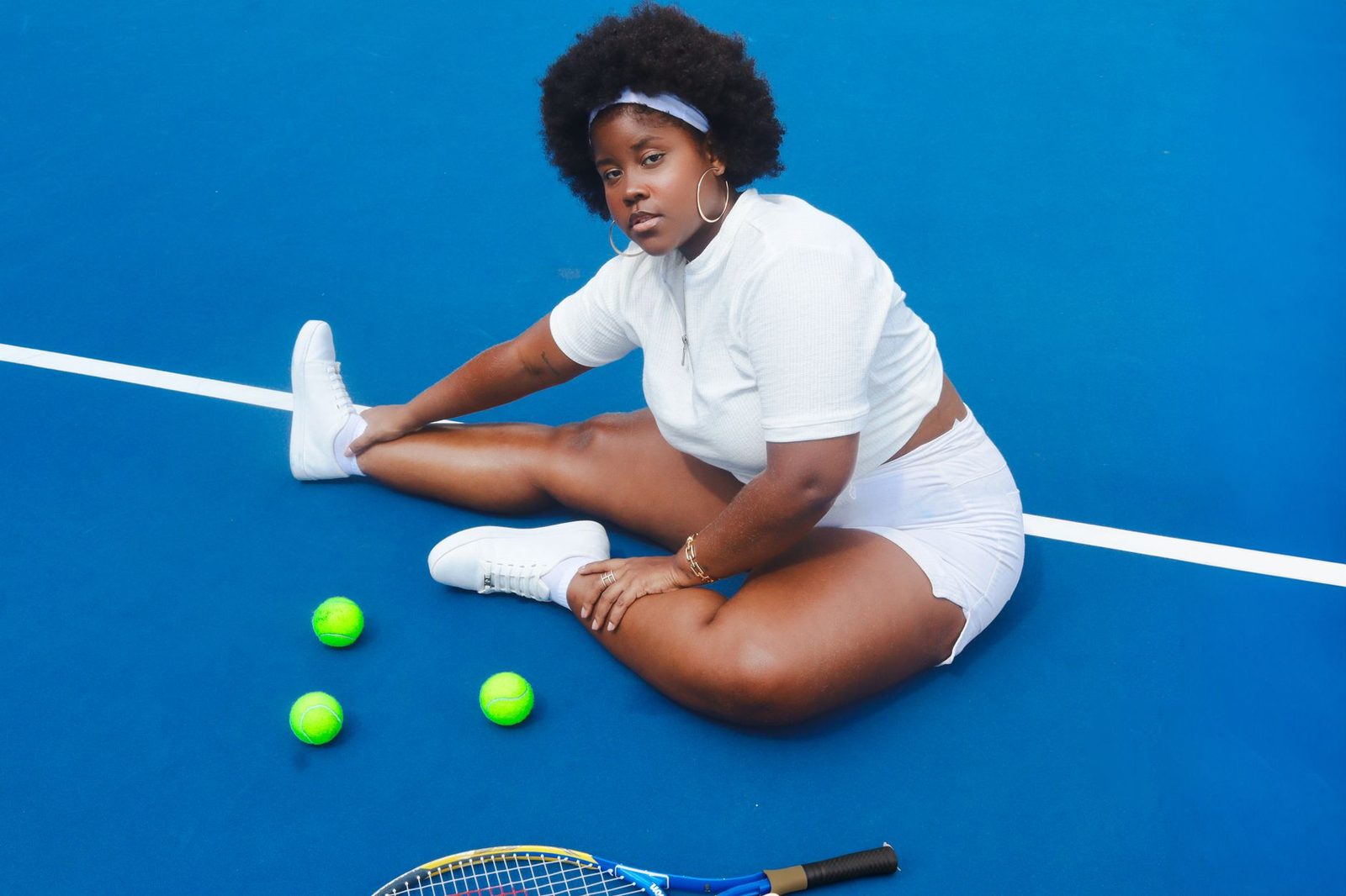 Player in athletic wear sitting on a tennis court with a racquet before playing
