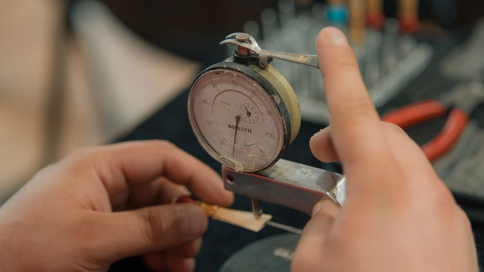 Hands taking a precise measurement with an analogue dial indicator