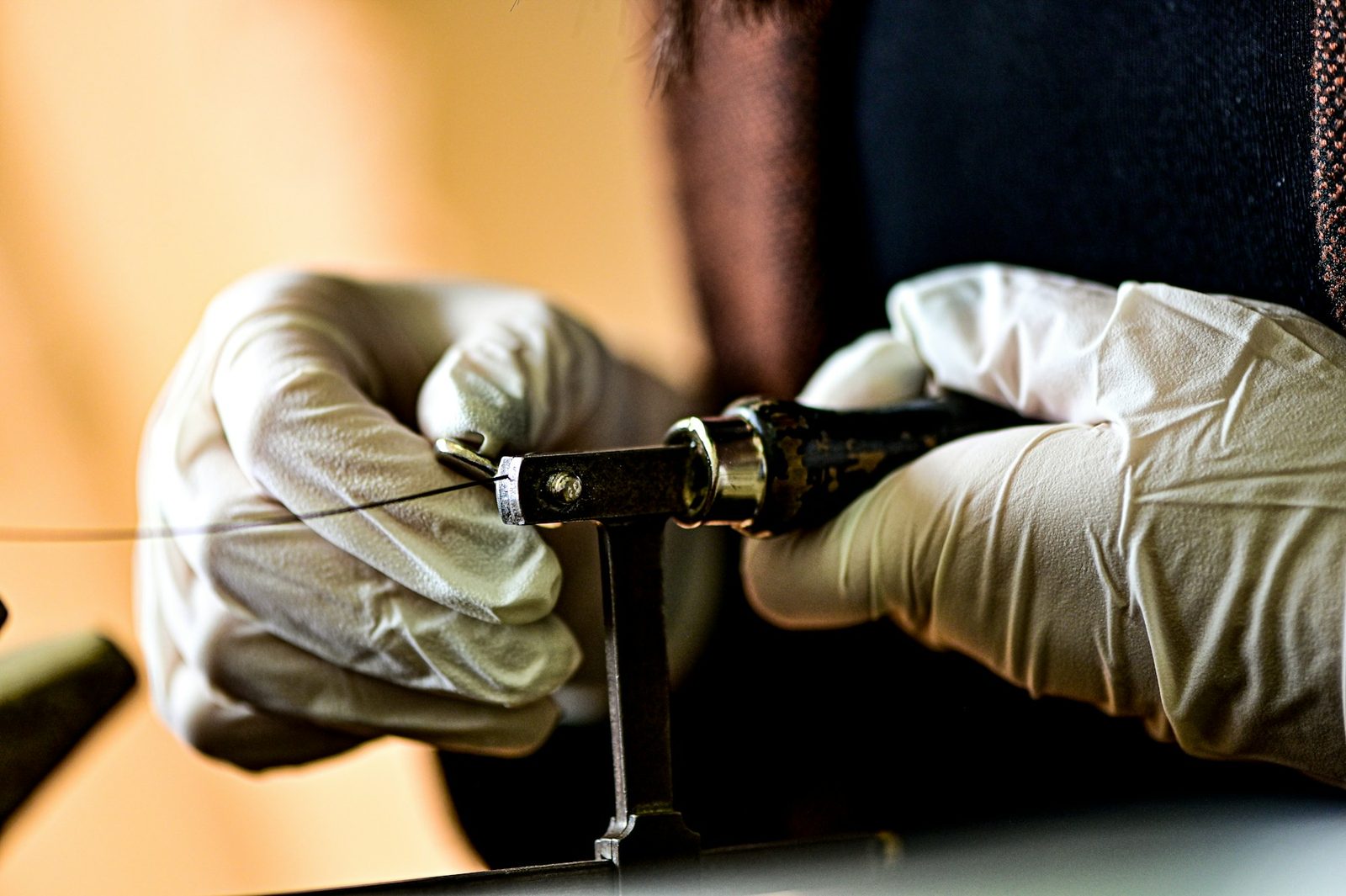Close-up of a person threading string through a frame by hand