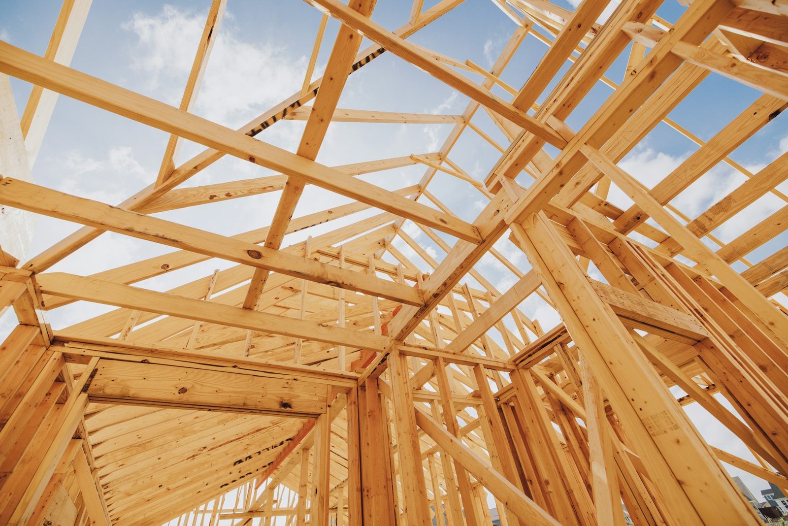 A timber frame structure under construction against a blue sky