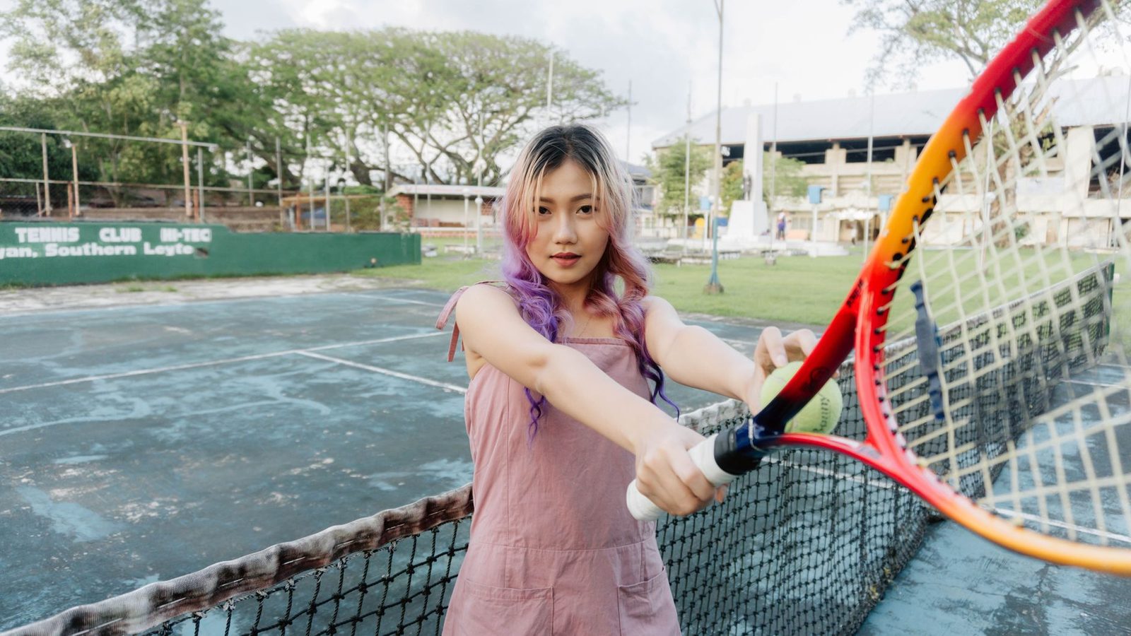 A young woman with a tennis racquet on an outdoor court