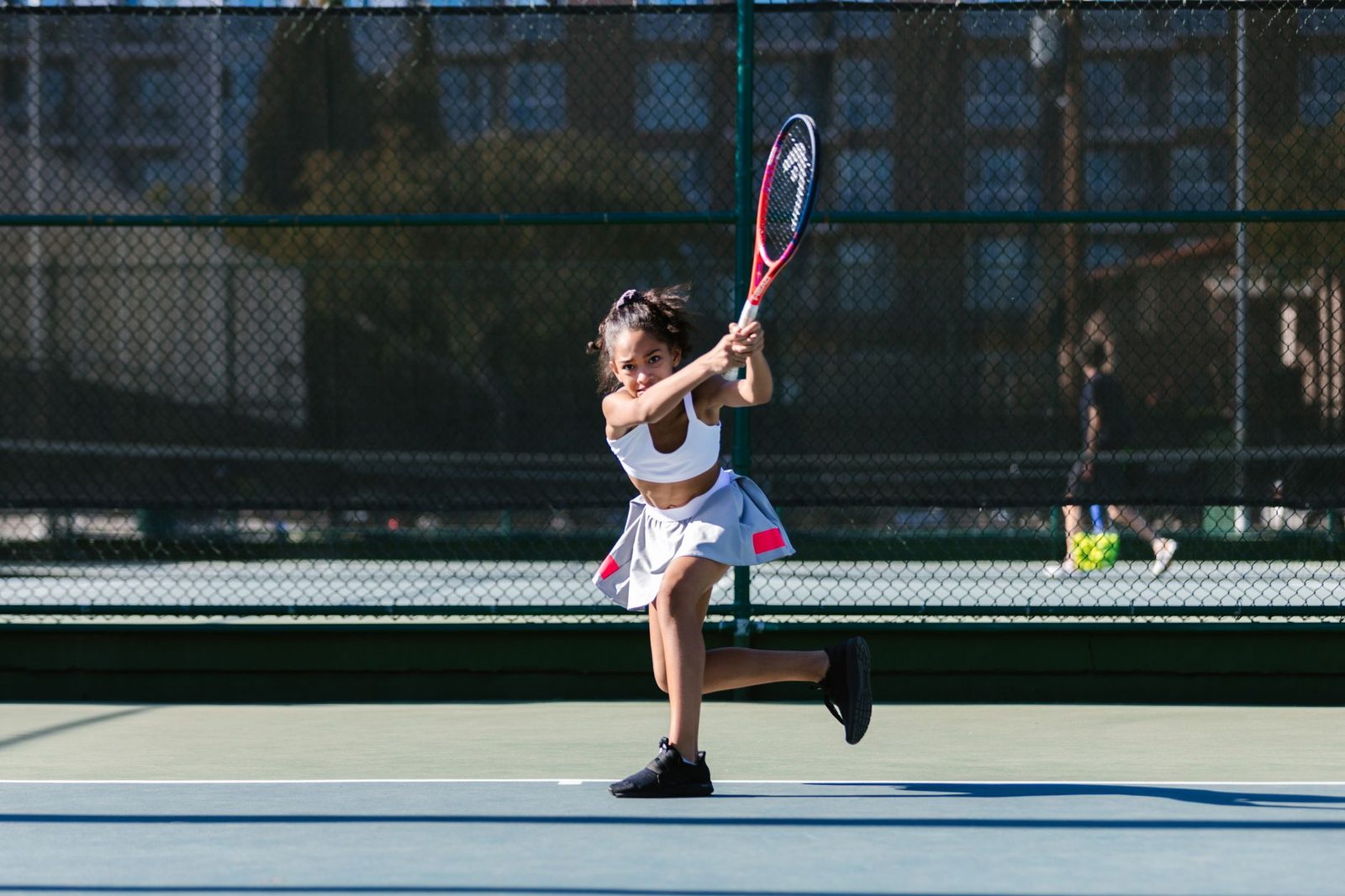 Young player striking a two-handed backhand on an outdoor court