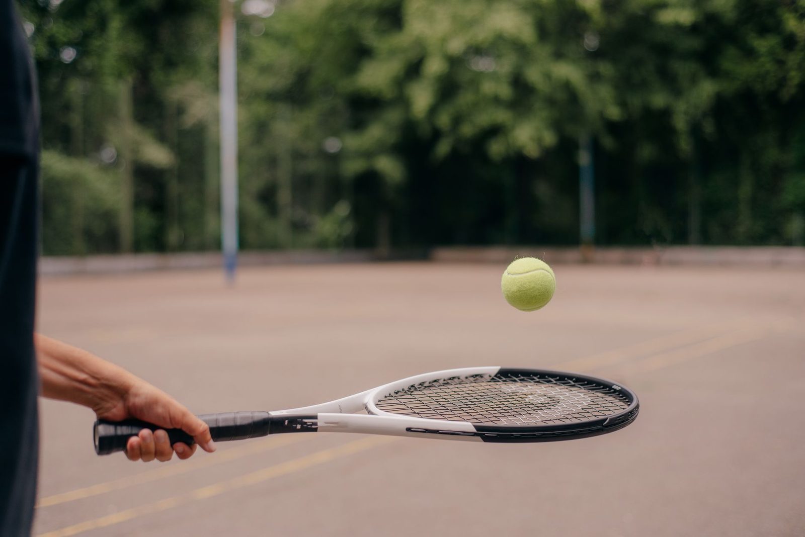 Close view of a tennis racquet and ball on an outdoor court