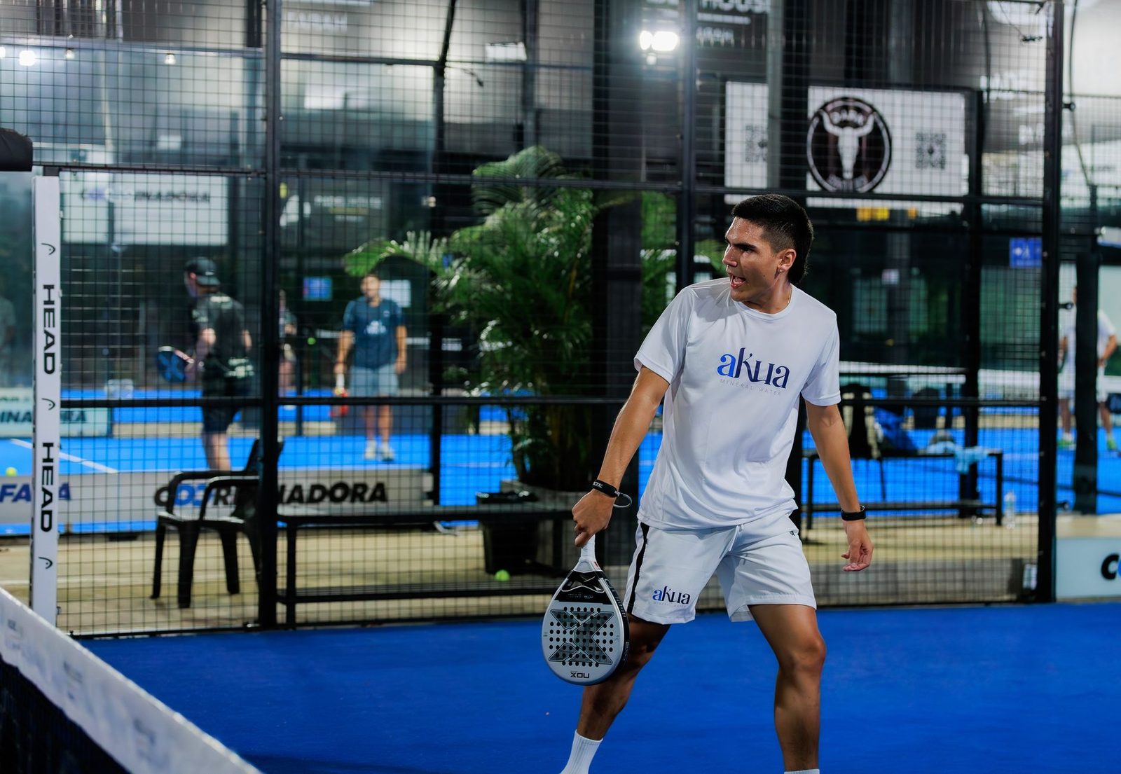 Padel player moving to the back of an indoor court mid-rally