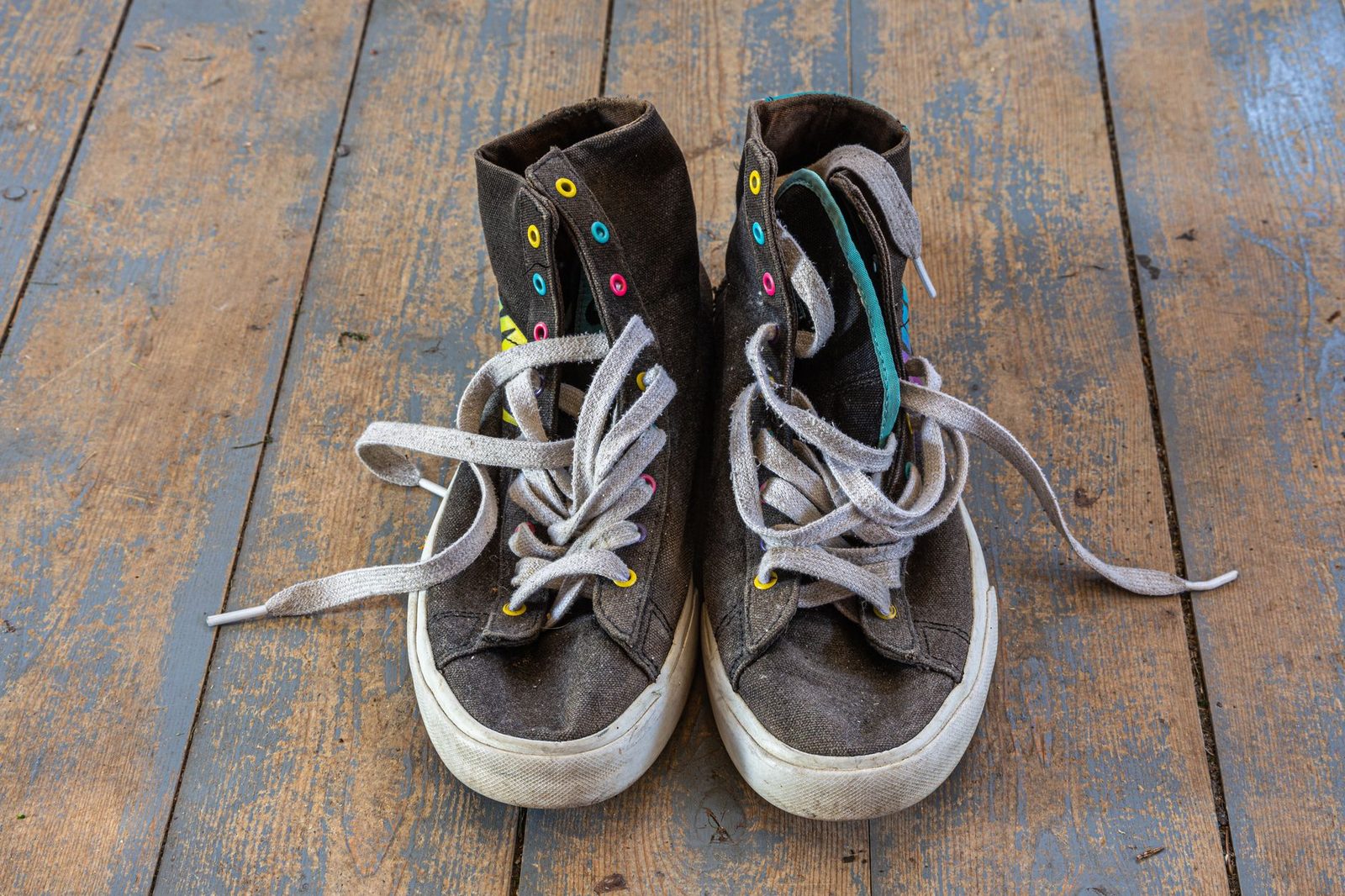 Old worn high-top trainers on a wooden floor