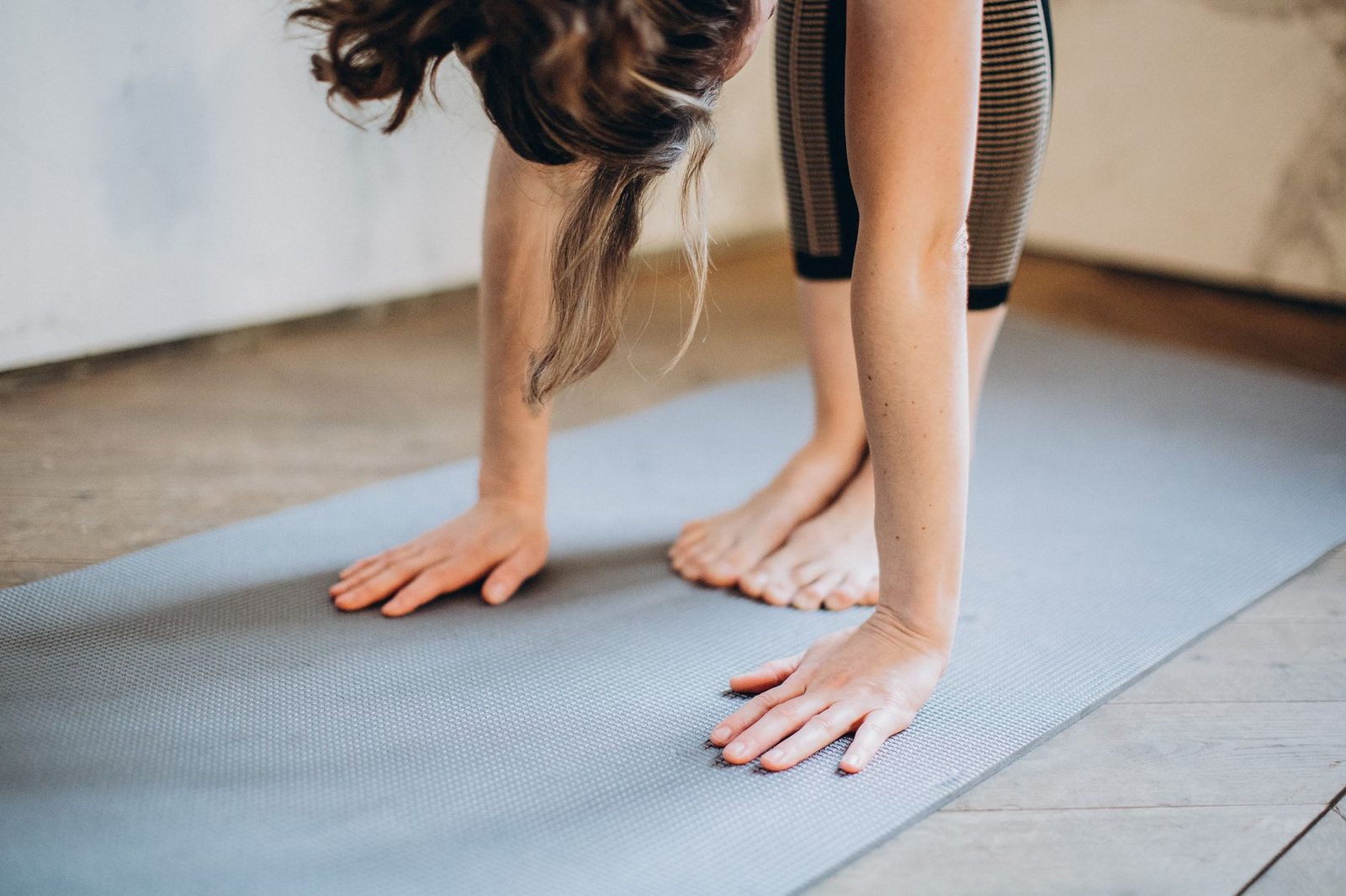 A woman performing a forward bend yoga pose on a mat